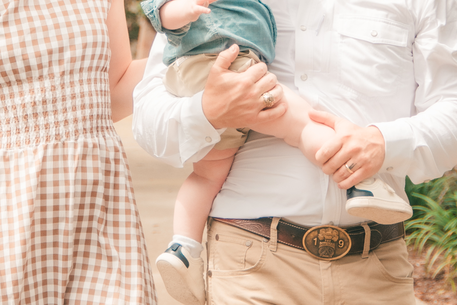 Close-up of dad holding his baby, mom's gingham dress beside them