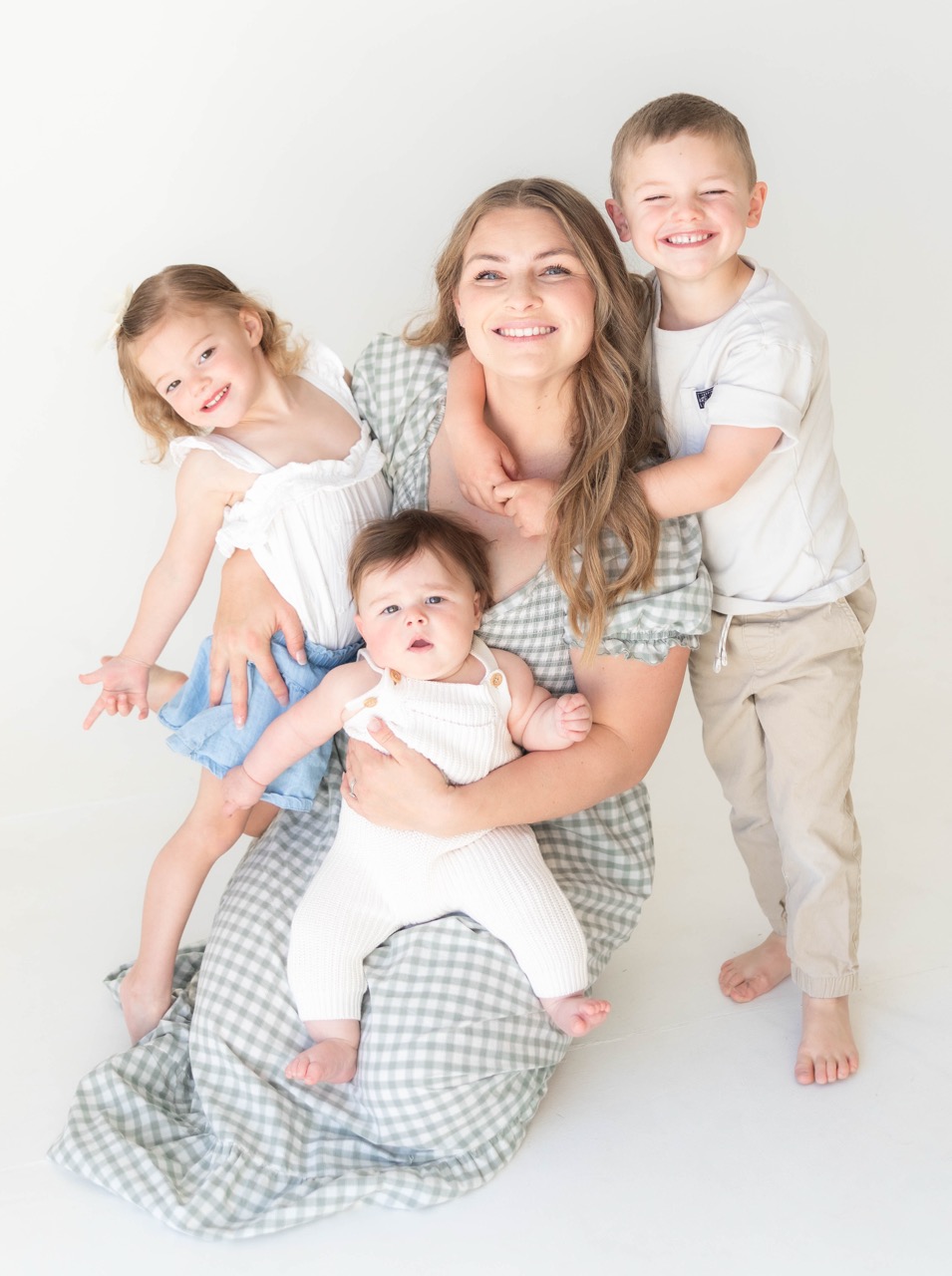 Mom kneeling in the studio surrounded by her three children, all smiling at the camera