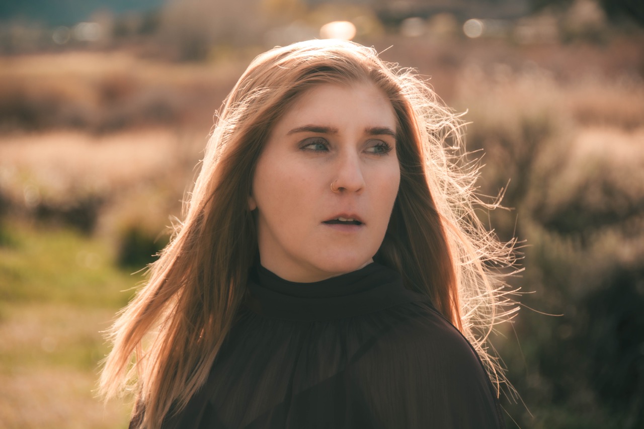 Backlit close-up portrait of a woman with the wind moving through her hair at golden hour
