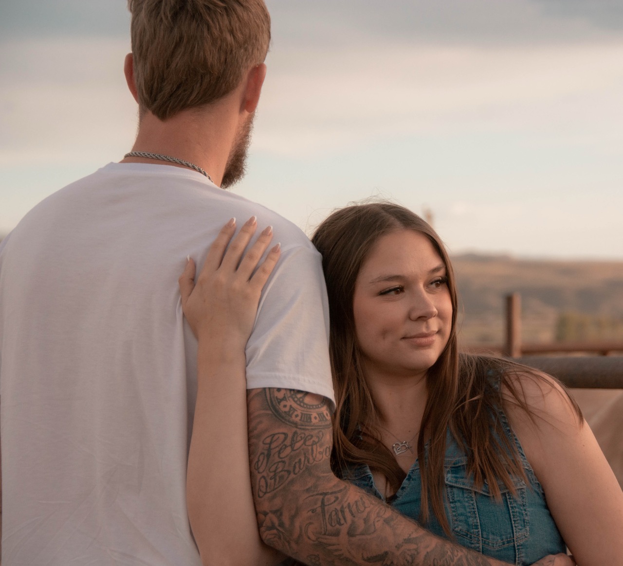 Ashley leaning her head on Kevin's shoulder, hand on his back, looking out toward the mesa