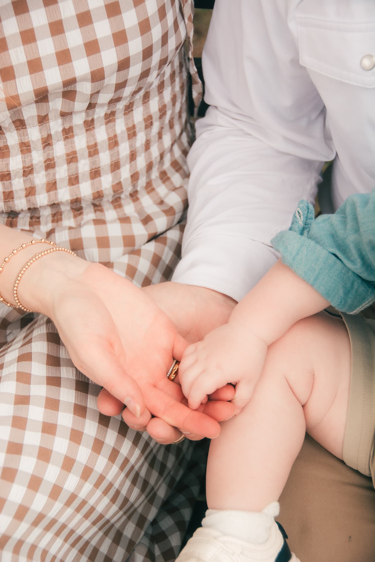 Close-up of mom's and dad's hands wrapped around their baby's tiny hand
