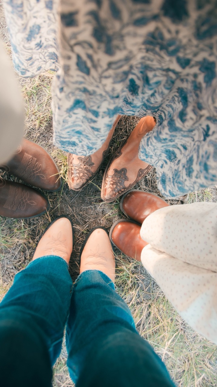 Overhead photo of four pairs of boots in a circle on the grass