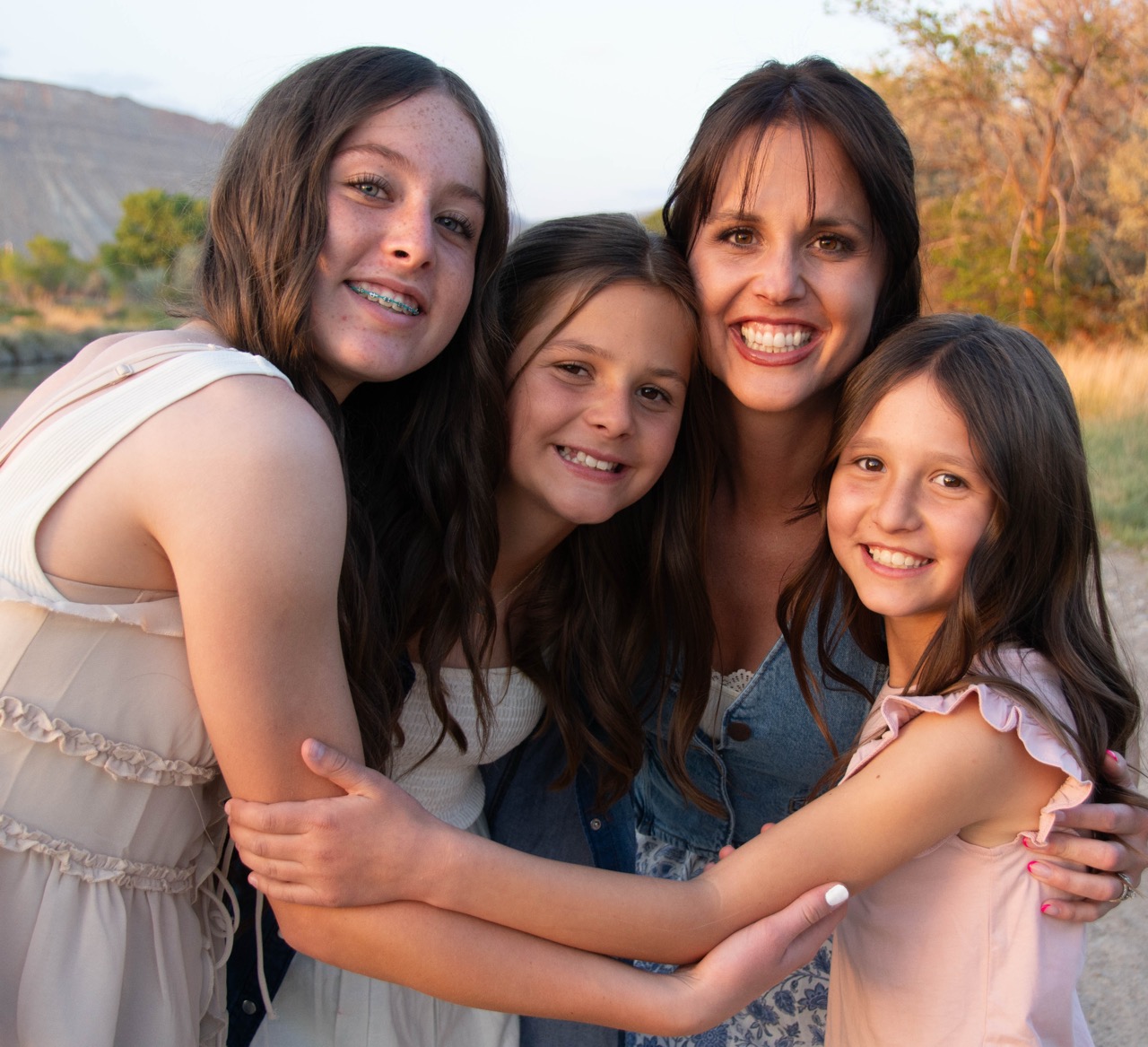 Close-up of mother and three daughters in a tight, smiling hug